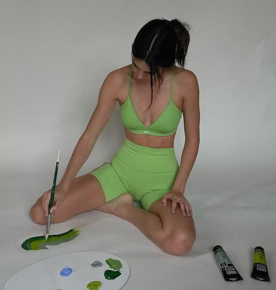Kendall Jenner wearing green ALO Yoga sports bra and matching set while painting.